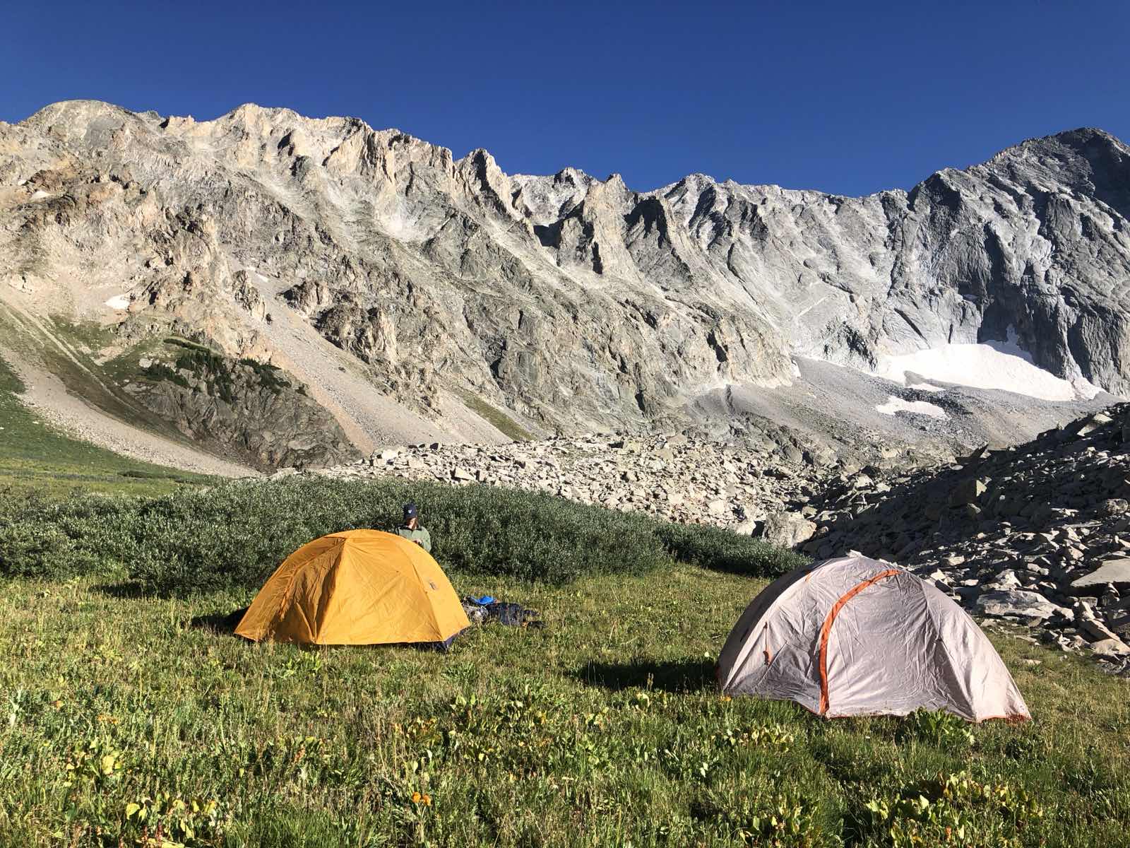 A backpacking tent set up on a hazy ridge above a forested valley.