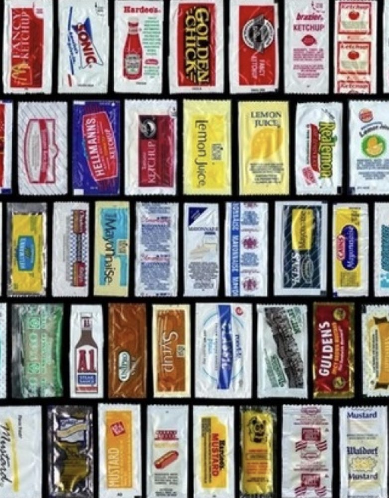 Small fast-food-style condiment packets laid out for a backpacking cook kit.